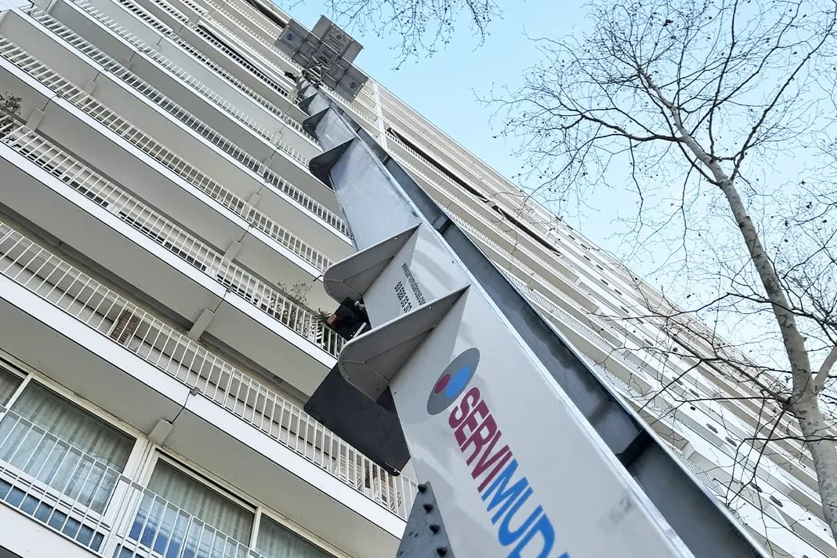 Plataforma elevadora Servimudanzas desde abajo en fachada de edificio alto