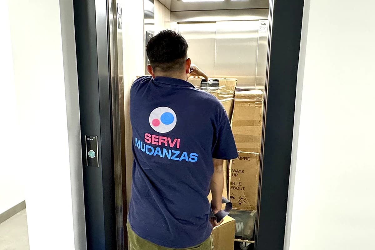 Mudanza con ascensor: operario de Servimudanzas cargando cajas en edificio