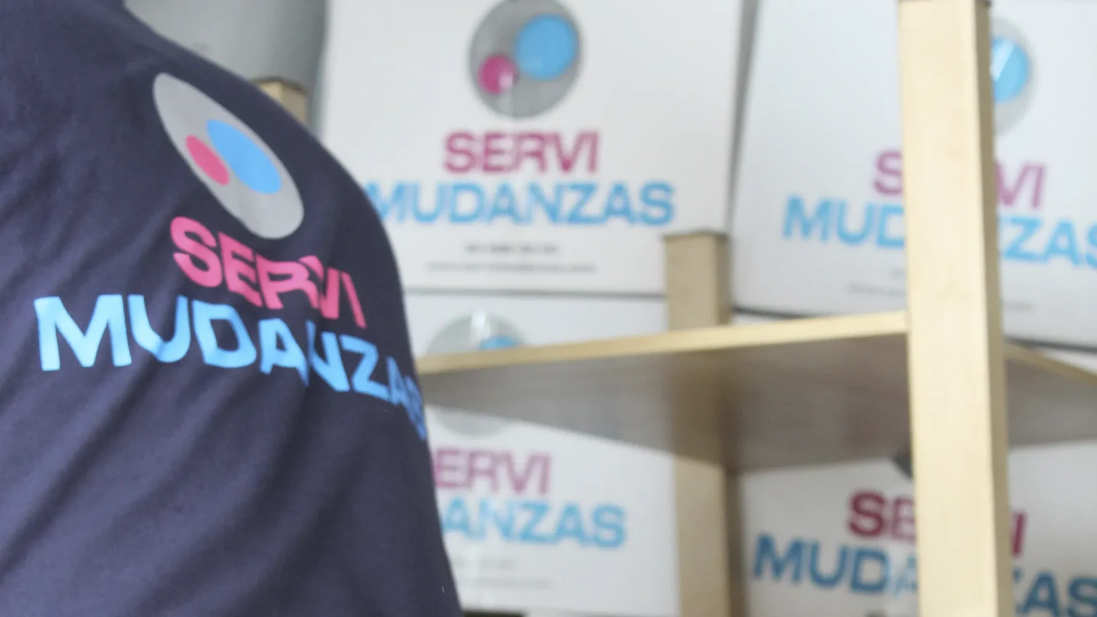 Operario de Servimudanzas con uniforme corporativo junto a cajas de mudanza marca apiladas