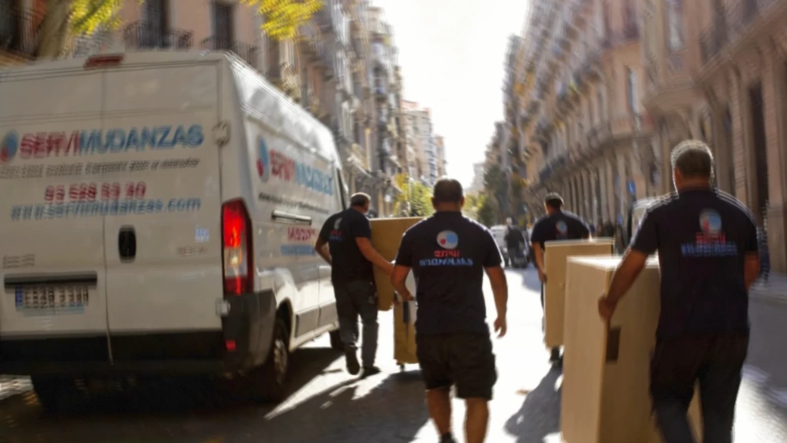 Operarios de Servimudanzas cargando furgoneta de mudanza en calle del Eixample, Barcelona