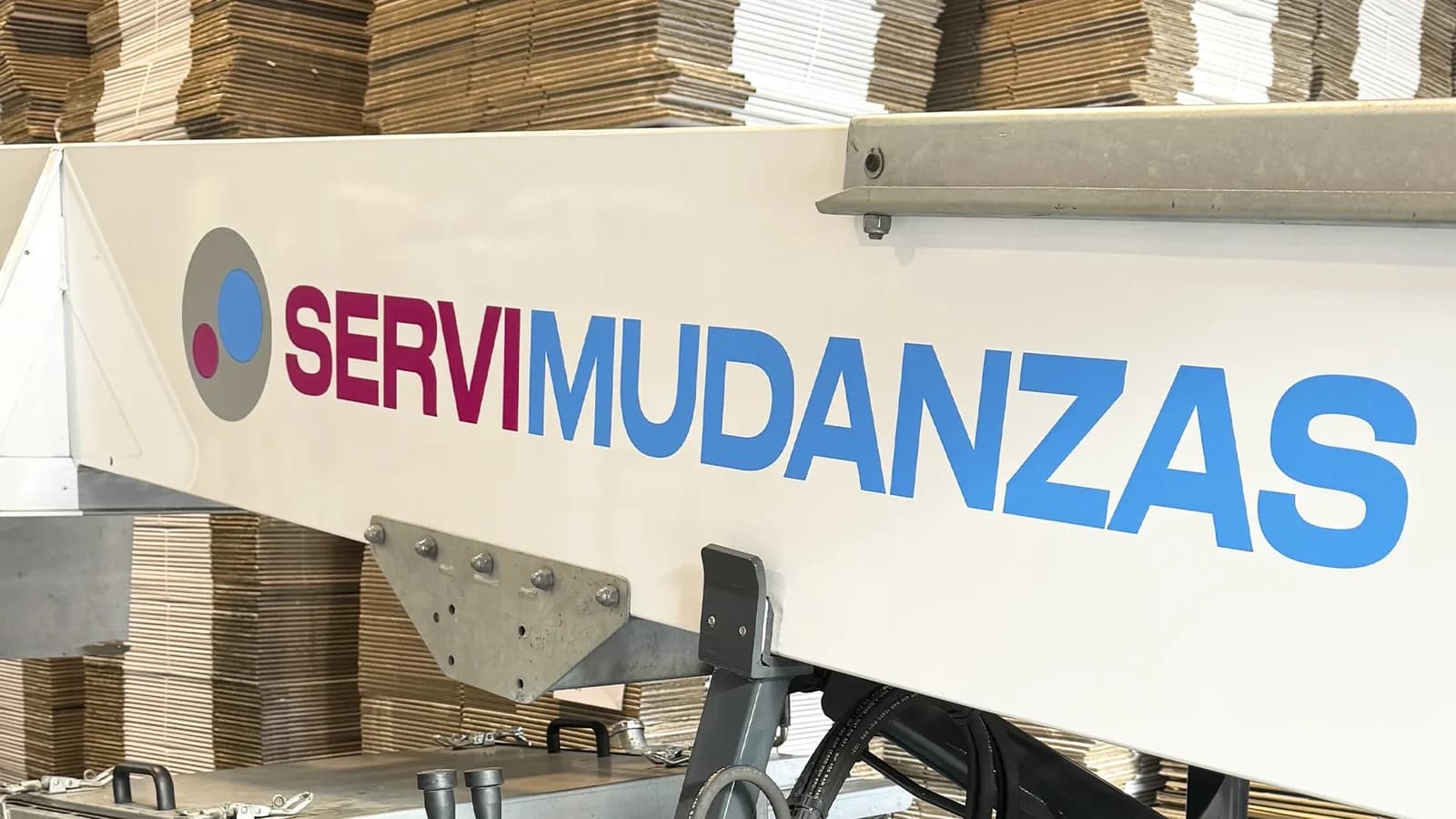 Detalle de la plataforma elevadora de Servimudanzas con cajas de cartón apiladas en el almacén